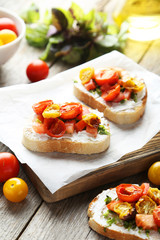 Tasty fresh bruschetta with tomatoes on cutting board on grey wo