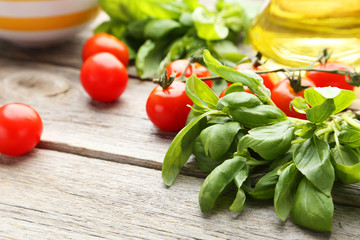 Tomatoes and basil leaves on grey wooden background