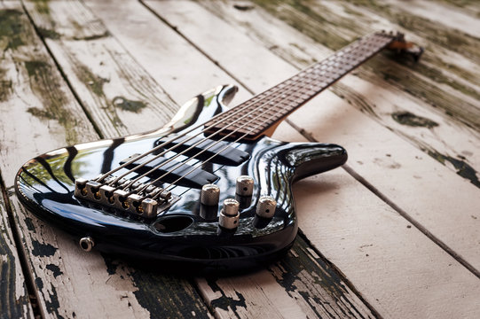 Black active five string bass guitar on a wooden background. color image in horizontal orientation