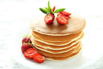 Tasty pancakes with strawberry on white wooden background