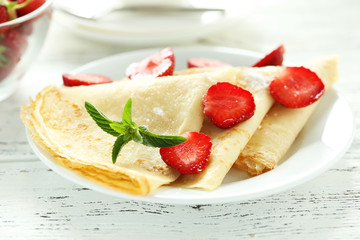 Tasty pancakes with strawberry on white wooden background