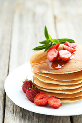 Tasty pancakes with strawberry on grey wooden background