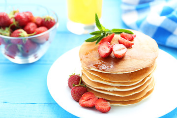 Tasty pancakes with strawberry on blue wooden background