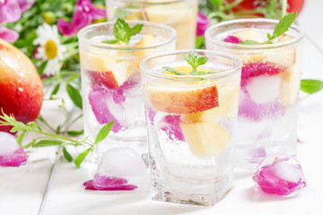 Fresh sparkling beverage with peaches and ice with rose petals o