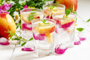 Fresh sparkling beverage with peaches and ice with rose petals o