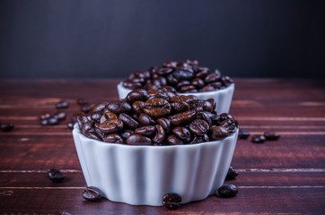 roasted coffee beans in two white bowl porcelain on wooden backg