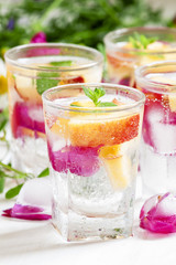 Fresh sparkling beverage with peaches and ice with rose petals o