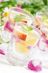 Fresh sparkling beverage with peaches and ice with rose petals o