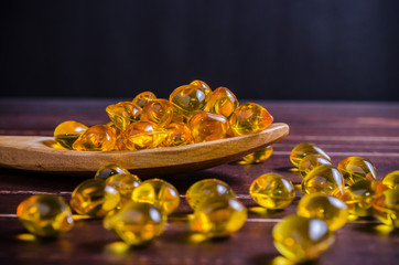 Fish oil on wooden spoon with wooden texture background