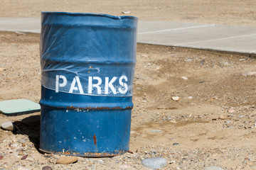 Metal barrel trash can stenciled with the word "parks"
