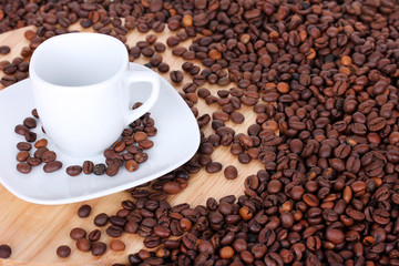 White cup with saucer on coffee beans