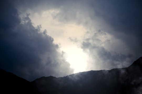 Mountains and Sky - Mountain scenery with dramatic clouds, sun and haze - computer generated image