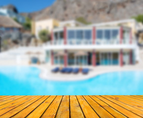 Wood table in perspective. Blurred hotel with pool