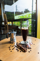 a moka pot and a cup of coffee with roasted coffee beans