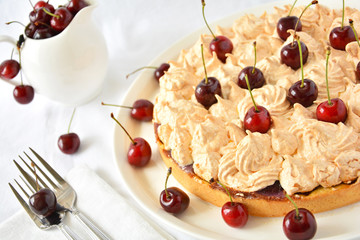 Homemade meringue cake with cherry on white table cloth