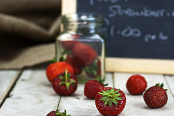 Stawberries in a jar and spilt on table