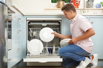 Man Loading Dishwasher In Kitchen