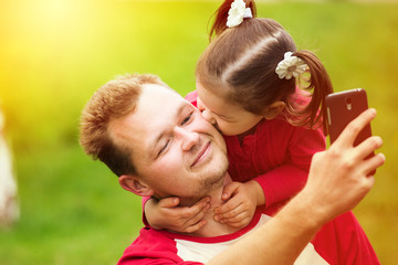 little girl kissing her father on cheek while taking selfie