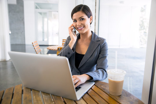 Executive Finance Real Estate Agent At A Coffee Shop Working On A Laptop And Talking On The Cell Phone