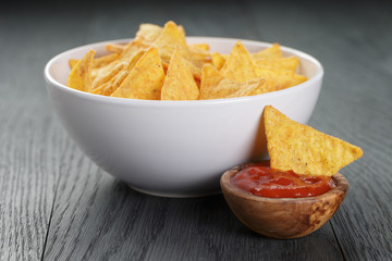 tortilla chips in white bowl with tomato sauce on wooden table