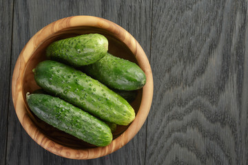 whole cucumbers in olive dowl on wood table
