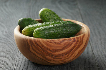 whole cucumbers in olive dowl on wood table
