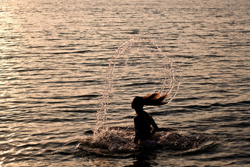 Young girl splashing water with her hair in the sea