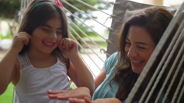 Happy family playing games outdoors, beautiful mother with cheerful daughter laughing, having fun together, spending summer day on hammock, Full HD Video 1920x1080