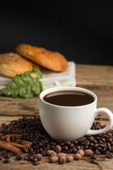Coffee cup and coffee bean on a wooden table. Dark background.