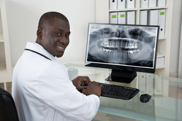 Dentist With Teeth X-ray On Computer
