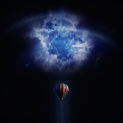 Abstract Balloon lost in space. Hot air balloon flying against blue night sky background. Cloudy...