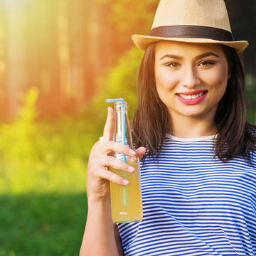 Happy young woman with bottle of lemonade in summer