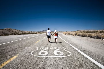 Gordijnen Route 66 - Couple of tourists walking on the famous highway © donvictori0