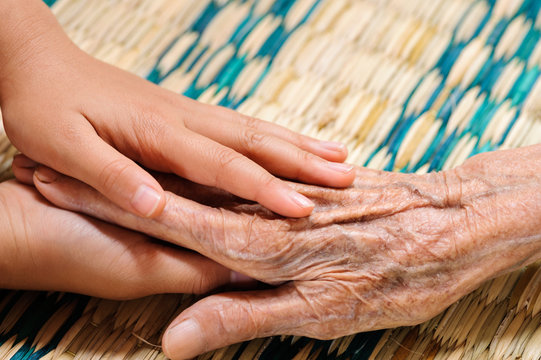 Young hand touches and holds an old woman hands
