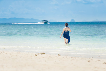 Girl walking in the sea at white sand beach