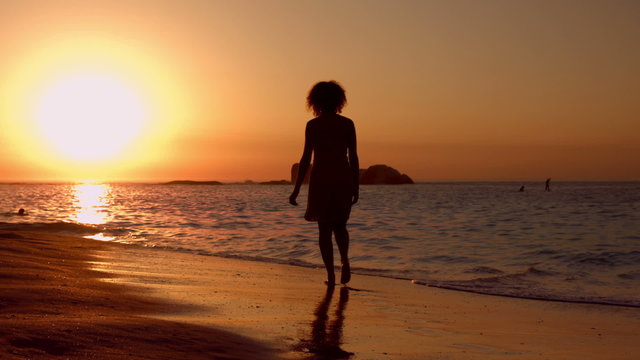 Woman walking on beach during sunset
