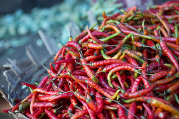 Pile of fresh fiery red hot chili peppers on display in rustic basket at an outdoor vegetable market in Mysore, India