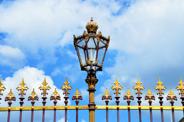 Fototapeta na wymiar Historischer vergoldeter Zaun aus Schmiedeeisen mit Laterne
