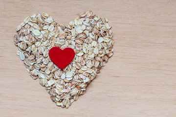 Oat flakes cereal heart shaped on wooden surface.