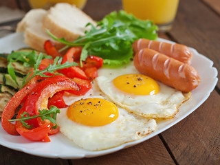 Fototapeta na wymiar English breakfast - fried eggs, sausages, zucchini and sweet peppers
