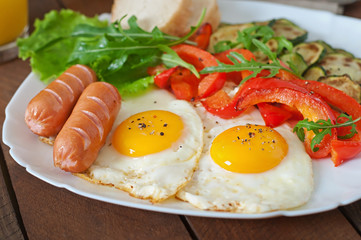 English breakfast - fried eggs, sausages, zucchini and sweet peppers