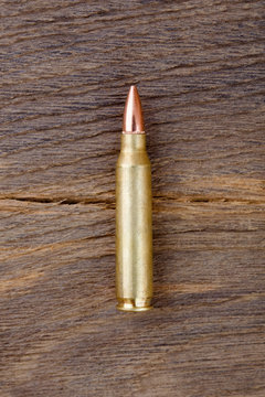 Close-up of rifle bulet on old wood desk.