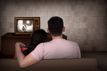 Young asian couple watching retro tv