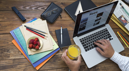 Morning digesting of news.
Man reading news at internet newspaper at sitting at wooden desk with...