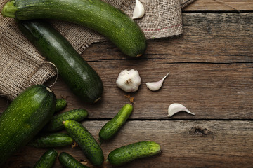 Zucchini, garlic and cucumbers on wooden background. Top view.