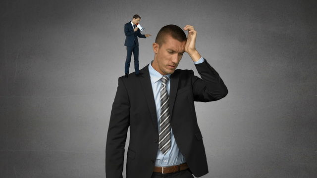 Small boss yelling on businessman with megaphone