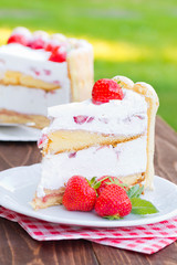 A slice of  the strawberry cake Charlotte. Light and creamy summer cake with fresh strawberries on a wooden background