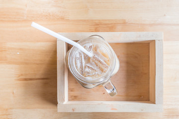 Iced coffee with milk is in Mason jar , on the table.