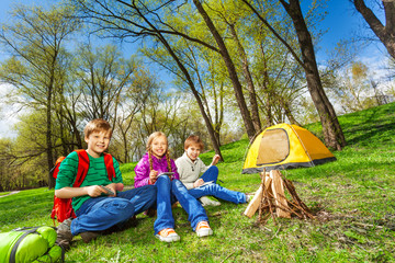 Happy children rest together near wooden bonfire