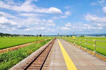 Fototapeta na wymiar Railroad and yellow line on platform at lavender-farm station in Furano, Hokkaido - Japan.